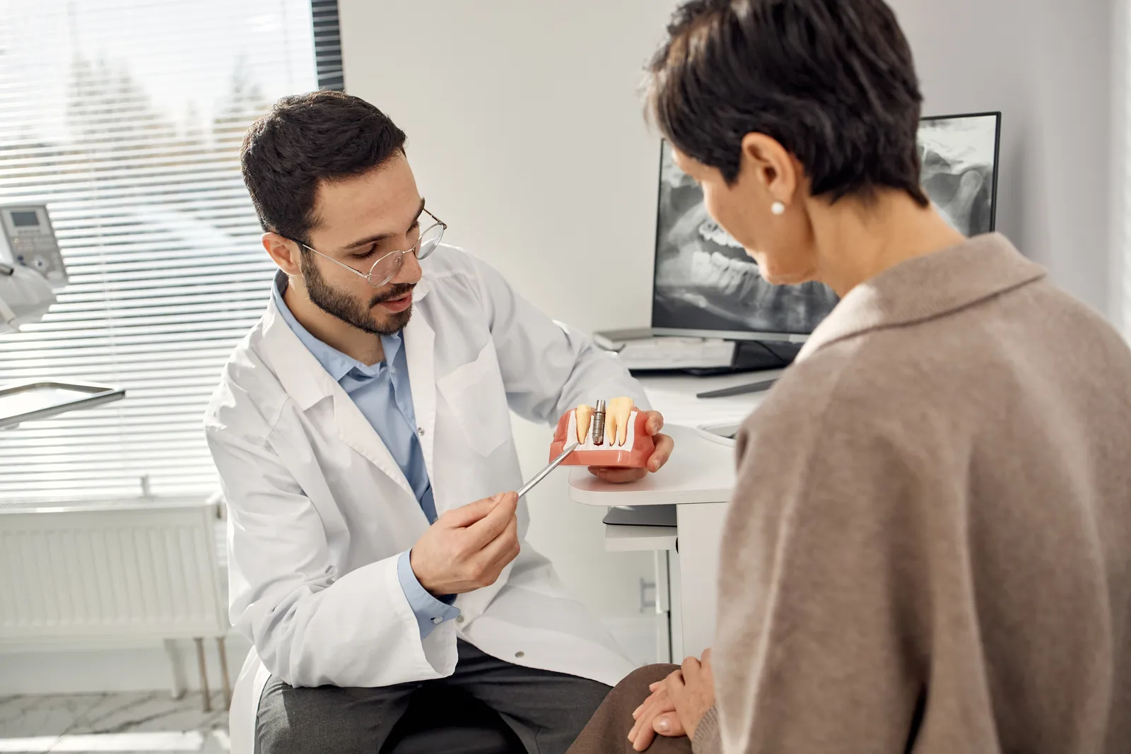 Dentist explaining a dental procedure to an older woman at a consultation