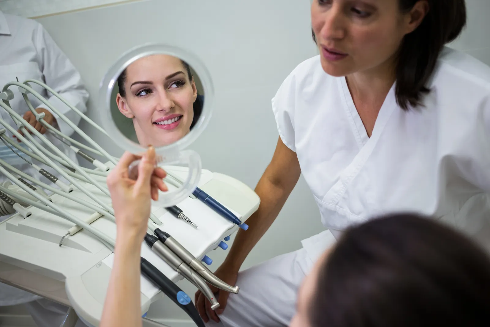 Patient checking her teeth in a hand mirror after treatment